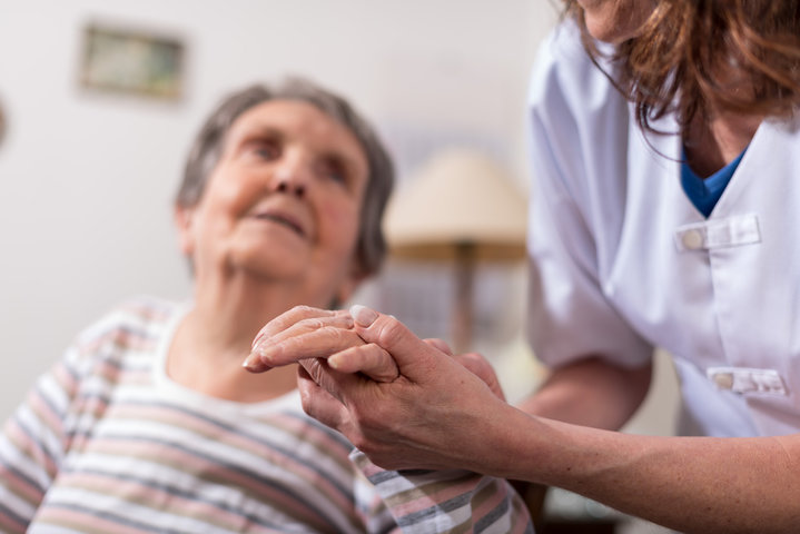 old person in a chair with carer helping them