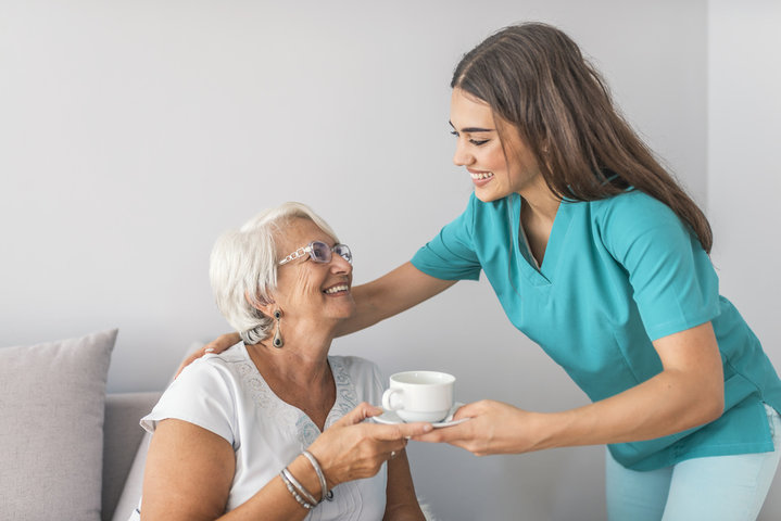woman receiving a cup of tea from care worker