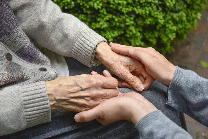older woman with hands being held