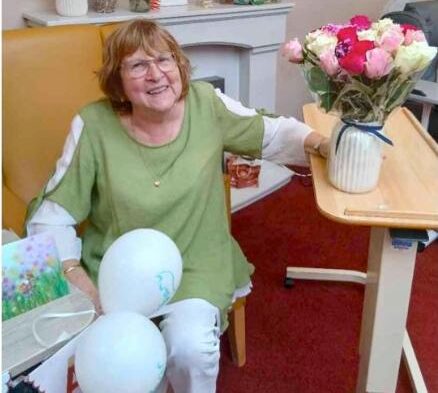 resident wearing a green top with flowers and balloons